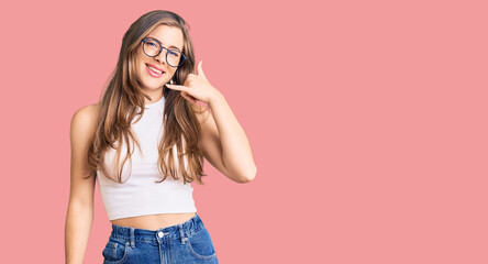 Beautiful caucasian young woman wearing casual clothes and glasses smiling doing phone gesture with hand and fingers like talking on the telephone. communicating concepts.