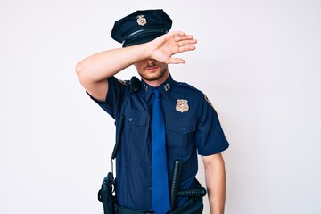 Young caucasian man wearing police uniform covering eyes with arm, looking serious and sad. sightless, hiding and rejection concept