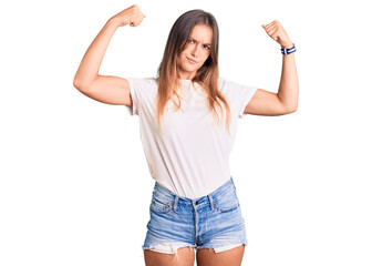 Beautiful caucasian woman wearing casual white tshirt showing arms muscles smiling proud. fitness...