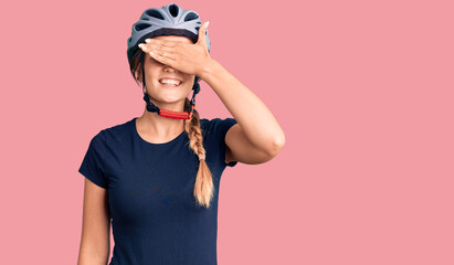 Beautiful caucasian woman wearing bike helmet smiling and laughing with hand on face covering eyes for surprise. blind concept.