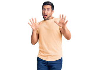 Fototapeta premium Young hispanic man wearing casual clothes afraid and terrified with fear expression stop gesture with hands, shouting in shock. panic concept.