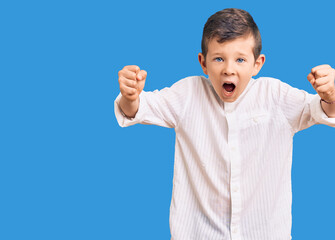 Cute blond kid wearing elegant shirt angry and mad raising fists frustrated and furious while...