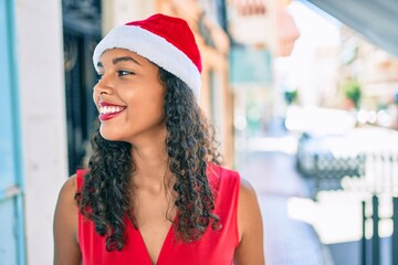 Young african american girl wearing christmas hat smiling happy at city.