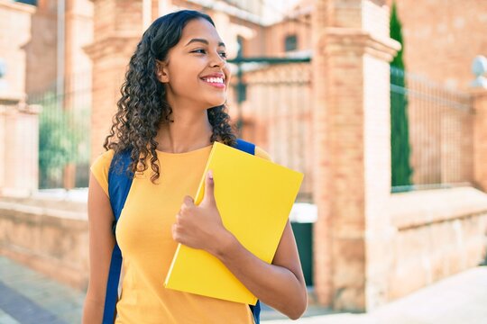 Young african american student girl smiling happy holding book at university campus.
