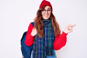 Young beautiful woman wearing winter scarf and student backpack smiling happy pointing with hand and finger to the side