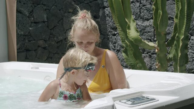 Mother with active and playful daughter in outside . Water is so refreshing and bathtub.