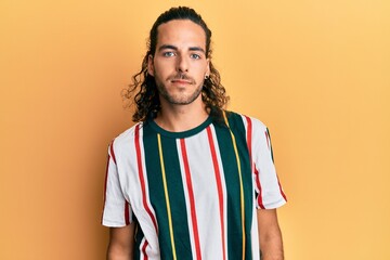 Young handsome man with long hair wearing casual clothes relaxed with serious expression on face. simple and natural looking at the camera.