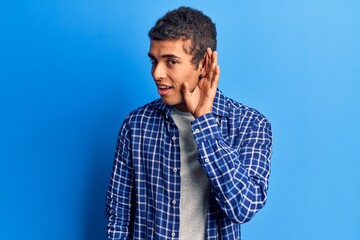 Young african amercian man wearing casual clothes smiling with hand over ear listening and hearing to rumor or gossip. deafness concept.