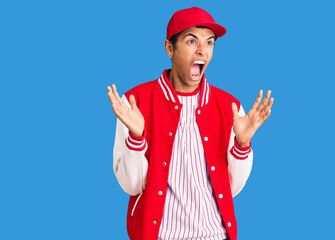 Young african amercian man wearing baseball uniform crazy and mad shouting and yelling with aggressive expression and arms raised. frustration concept.