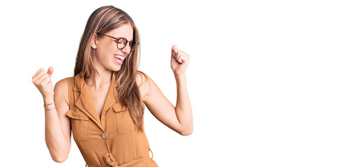 Young beautiful blonde woman wearing casual clothes and glasses dancing happy and cheerful, smiling moving casual and confident listening to music