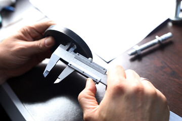The worker is measuring to holes of inner diameter of flange with vernier caliper gauge. Vernier...