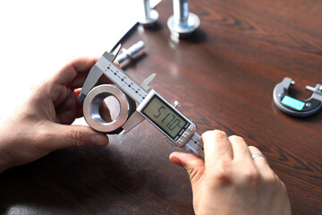 The worker is measuring to outer diameter of metal sleeve with vernier caliper gauge. Vernier...