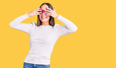 Beautiful brunette young woman wearing casual white sweater and glasses covering eyes with hands smiling cheerful and funny. blind concept.