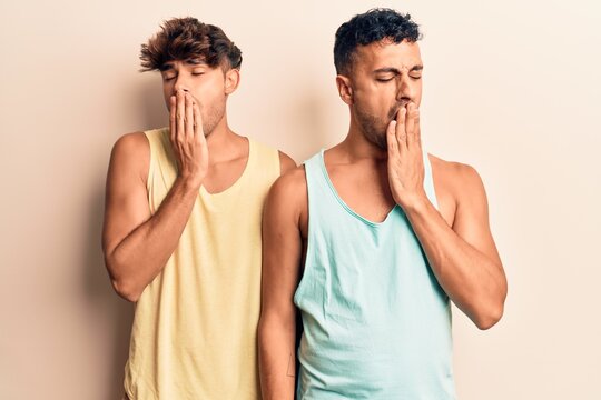 Young gay couple wearing casual clothes bored yawning tired covering mouth with hand. restless and sleepiness.