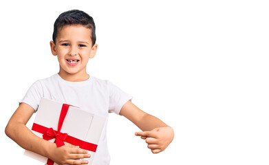 Little cute boy kid holding gift smiling happy pointing with hand and finger