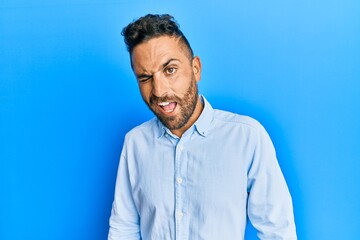 Handsome man with beard wearing casual clothes winking looking at the camera with sexy expression, cheerful and happy face.