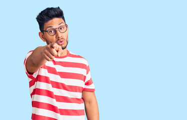 Handsome latin american young man wearing casual clothes and glasses pointing displeased and frustrated to the camera, angry and furious with you