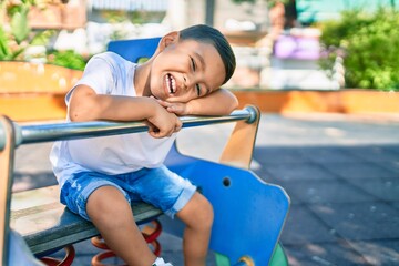 Adorable hispanic boy smiling happy playing at the park.