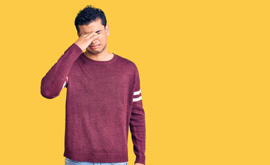 Hispanic handsome young man wearing casual clothes smelling something stinky and disgusting,...