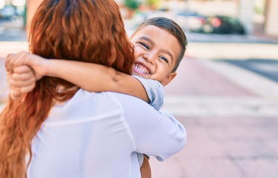 Adorable latin mother and son smiling happy hugging at the city.
