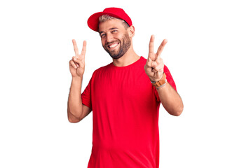 Young handsome blond man wearing t-shirt and cap smiling looking to the camera showing fingers doing victory sign. number two.