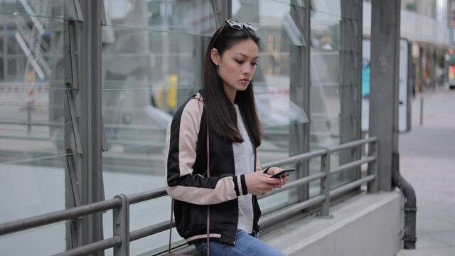Young Asian woman writes text messages on her phone - people photography