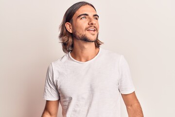 Young handsome man wearing casual clothes looking away to side with smile on face, natural expression. laughing confident.