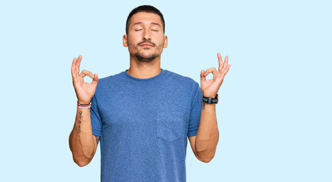 Handsome man with tattoos wearing casual clothes relax and smiling with eyes closed doing meditation gesture with fingers. yoga concept.