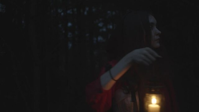 Red riding hood in dark woods with lantern, slow motion
