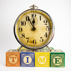 Vintage Alarm Clock On Top of Wood Blocks that Spell Time