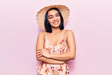 Young beautiful latin woman wearing summer hat happy face smiling with crossed arms looking at the camera. positive person.