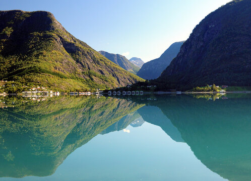Mountains Reflecting In The Calm Water Of The Dalsfjord Near Skjolden On A Sunny Summer Day With A Clear Blue Sky And A Few Clouds