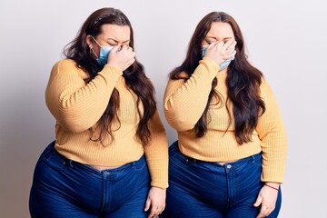 Young plus size twins wearing medical mask tired rubbing nose and eyes feeling fatigue and headache. stress and frustration concept.