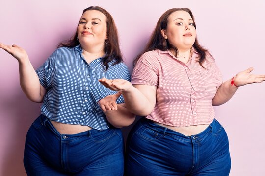 Young plus size twins wearing casual clothes clueless and confused expression with arms and hands raised. doubt concept.