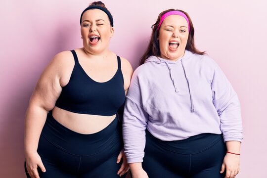 Young plus size twins wearing sportswear winking looking at the camera with sexy expression, cheerful and happy face.