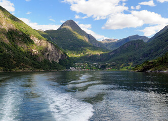 View From A Boat To Geiranger Village In The Geirangerfjord On A Sunny Summer Day With A Clear Blue Sky And A Few Clouds