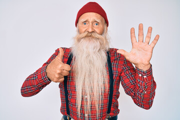 Old senior man with grey hair and long beard wearing hipster look with wool cap showing and pointing up with fingers number six while smiling confident and happy.