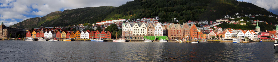 Panorama View To The Historic Painted Wooden Houses Of Bryggen In Bergen On A Sunny Summer Day With A Clear Blue Sky And A Few Clouds