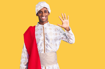 African handsome man wearing tradition sherwani saree clothes showing and pointing up with fingers number five while smiling confident and happy.