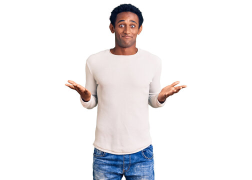 African handsome man wearing casual winter sweater clueless and confused expression with arms and hands raised. doubt concept.