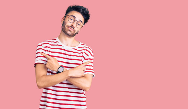 Young hispanic man wearing casual clothes pointing to both sides with fingers, different direction disagree