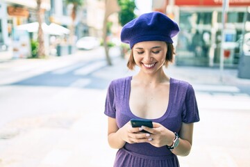 Young beautiful girl smiling happy with french style using smartphone at street of city
