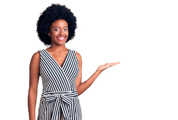 Young african american woman wearing casual clothes smiling cheerful presenting and pointing with palm of hand looking at the camera.