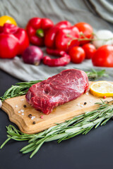 Raw beef steak on a cutting board with spices. Creative atmospheric decoration