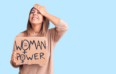 Young beautiful woman holding woman power banner stressed and frustrated with hand on head, surprised and angry face