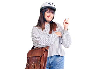 Young plus size woman wearing bike helmet and leather bag smiling happy pointing with hand and finger to the side