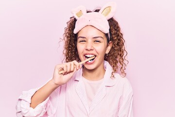 Beautiful latin teenager wearing pajama and sleep mask smiling happy. Standing with smile on face...