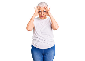 Senior beautiful woman with blue eyes and grey hair wearing casual white tshirt trying to open eyes...