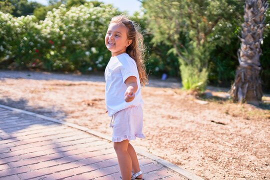 Adorable blonde child smiling happy. Standing with smile on face walking around the park