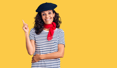 Middle age beautiful woman wearing french beret and scarf smiling happy pointing with hand and finger to the side